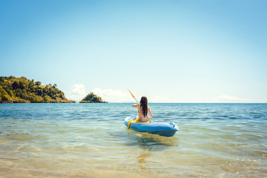 在清澈的海水中划着皮划艇享受夏天的女人
