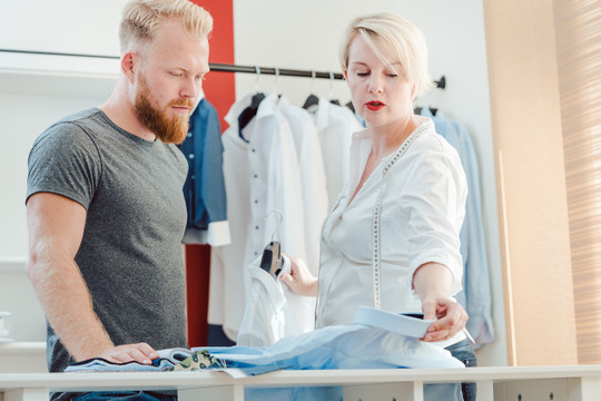 裁缝和客户查看样式手册，选择衬衫和套装的材料