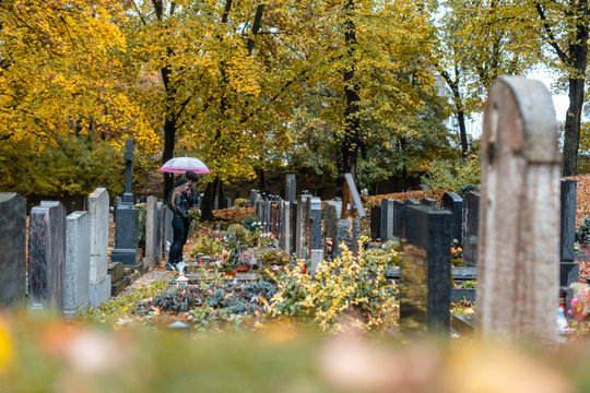 秋天墓地上的坟墓，一对夫妇站在坟墓之间哀悼死者