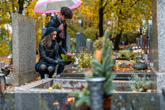 秋天下雨时，一对夫妇在墓地悲伤
