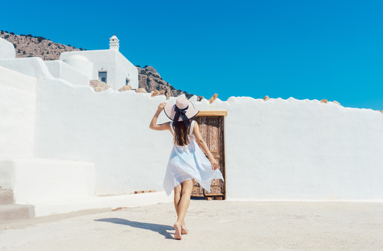 一个女人走近一栋希腊式的白墙房子
