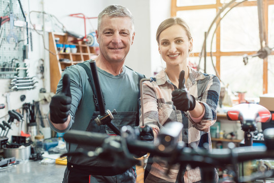 两位自行车修理工在他们的车间成功地展示了他们的大拇指
