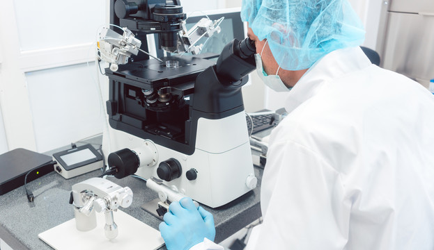 在生物技术实验室通过显微镜观察的医生或科学家