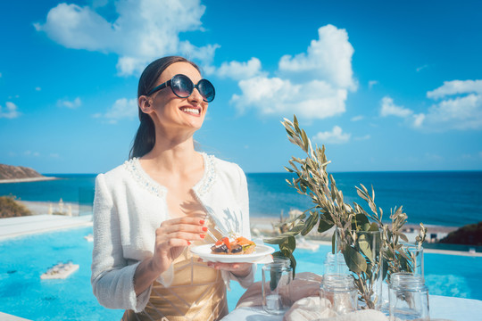 在海滩屋派对上享受美食的女人，有大海和游泳池