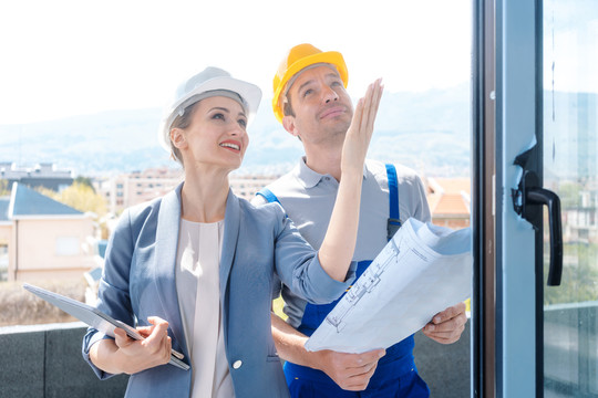 女建筑师和建筑工人在现场检查窗户