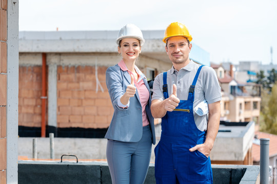 现场的建筑师和建筑工人竖起大拇指对着摄像机