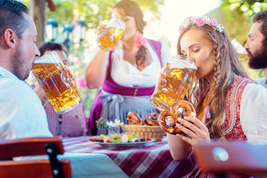 在朋友们的簇拥下喝着大量啤酒的特雷希特（Tracht）女人看着镜头