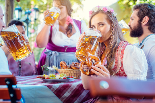 在朋友们的簇拥下喝着大量啤酒的特雷希特（Tracht）女人看着镜头