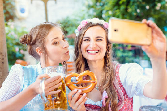 巴伐利亚州最好的朋友用手机、啤酒和椒盐卷饼自拍
