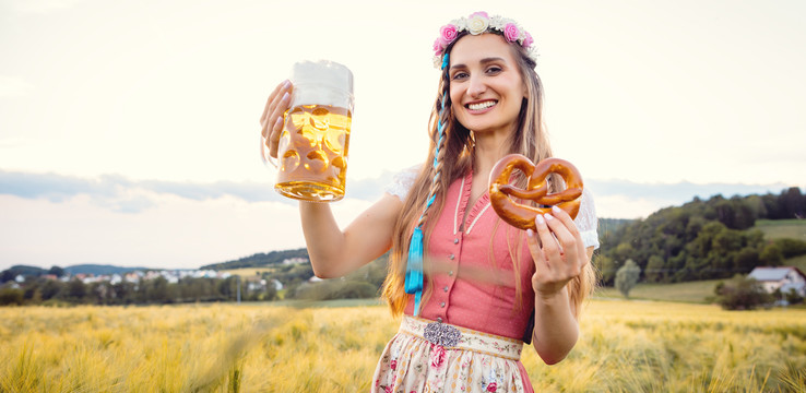 夏天日落时，一位快乐的巴伐利亚女人，喝着啤酒，吃着传统食物