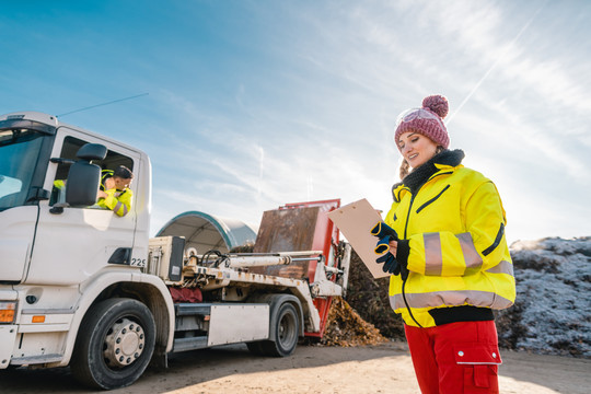 在堆肥厂登记卡车卸载生物质的女经理