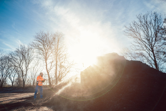 阳光明媚的日子里，工人正在检查堆肥厂的生物质堆