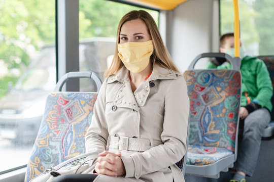 戴口罩的妇女在新冠病毒19型危机期间使用公共交通工具