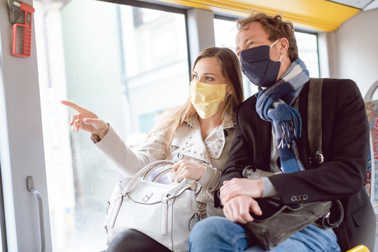 由于病毒大流行，公共交通大巴上的夫妇戴着口罩