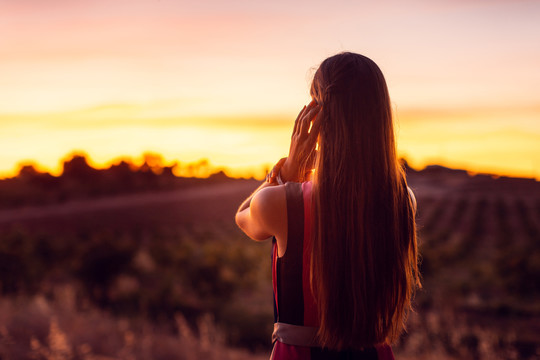 在橄榄林中看夕阳余晖的女人