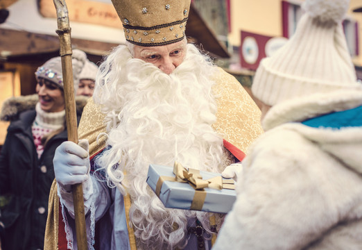圣·尼古拉斯和他的员工在圣诞市场上见面，并向一家人赠送礼物