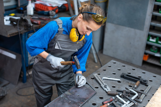 一名女工人正在专注于自己的工作，她正在标记一块金属