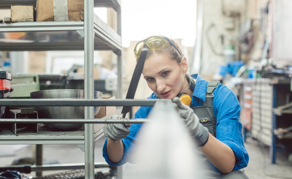 一名女金属工人手持钢锉检查工作的准确性