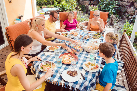 一家人在花园聚会，在餐桌旁吃饭，一起享受时光