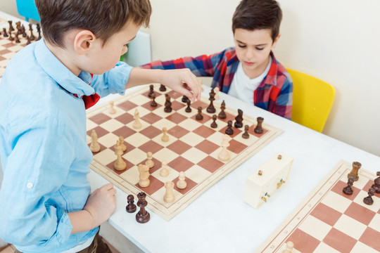 两个男孩在比赛中下棋，在棋盘上移动棋子