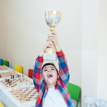 男孩兴奋地展示他在国际象棋比赛中赢得的奖杯