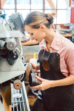 女鞋匠在制鞋车间操作机器调整设置