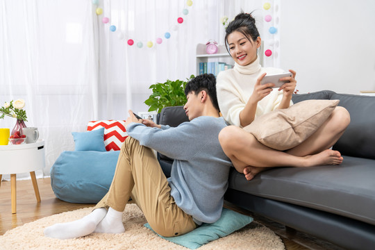 年轻情侣在家玩手机