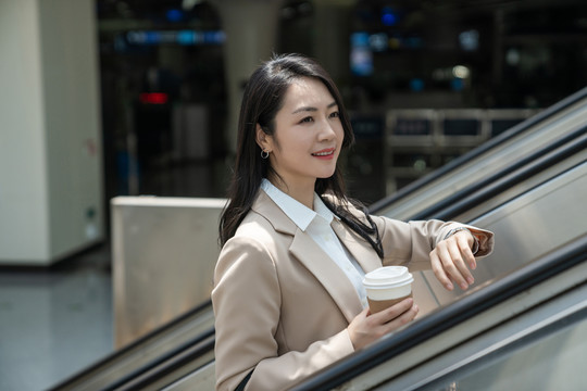 商务女士在机场拿着咖啡坐电梯