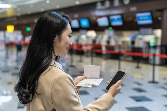 商务女士拿着护照在机场使用手机