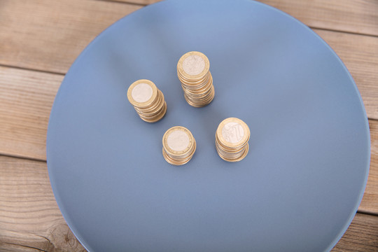 蓝色盘子里放着几摞欧元硬币