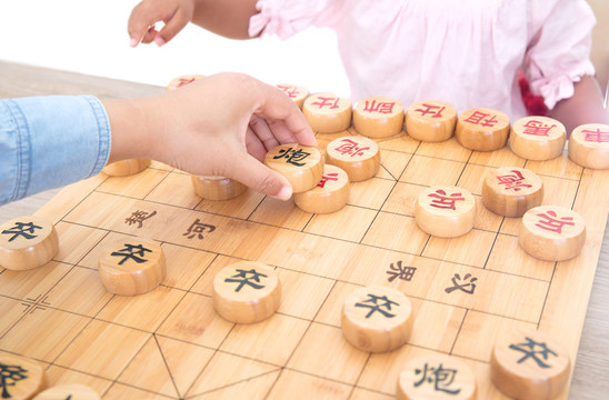 小女孩在和妈妈下中国象棋