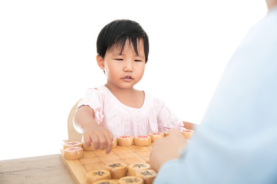 小女孩在认真的和大人下中国象棋