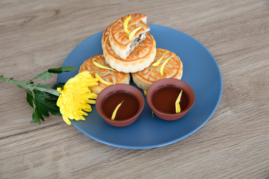 月饼和两碗茶水及菊花瓣