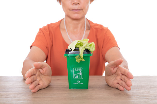 双手呵护着绿色的厨余垃圾桶和菜