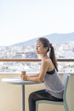 穿着运动服的亚洲女性坐在阳台上