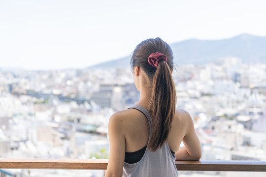 穿着运动服的亚洲女性坐在阳台上