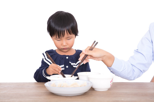 妈妈在帮助自己的女儿吃饺子