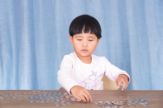 小女孩在摆弄桌子上的美元硬币