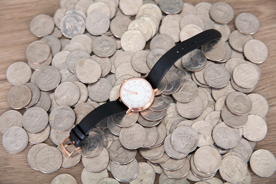 一堆美元硬币上放着一块腕表