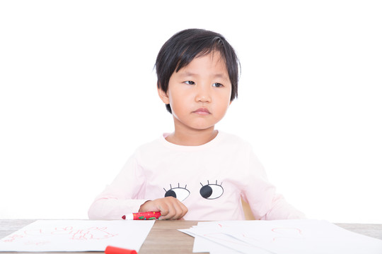 桌子前手拿画笔深思的中国小姑娘