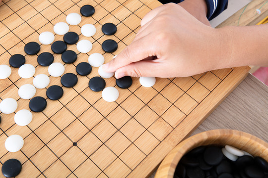 大人的手指导着小孩的手下围棋