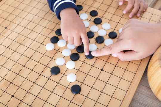 大人的手指导着小孩的手下围棋