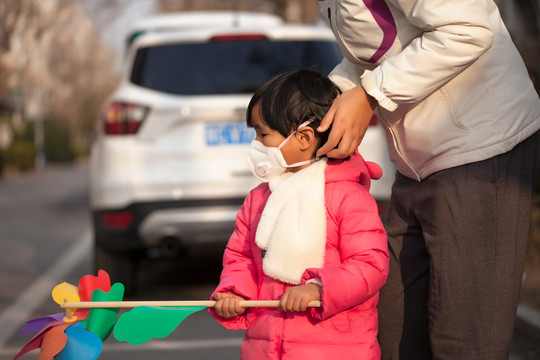 妈妈在给女儿整理戴着的口罩