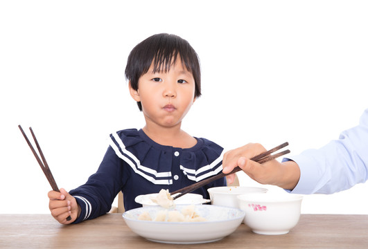 白背景前餐桌旁的小女孩在吃饭