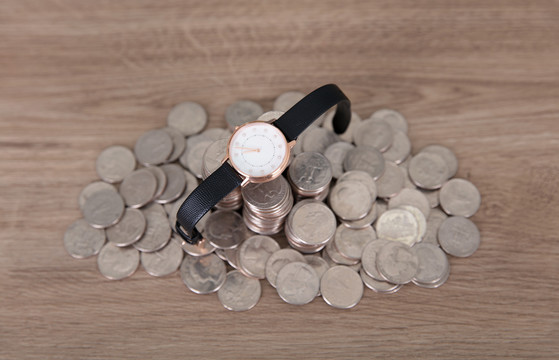 一堆美元硬币上放着一块手表