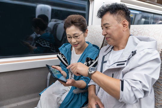 快乐的老年夫妇坐地铁使用平板电脑