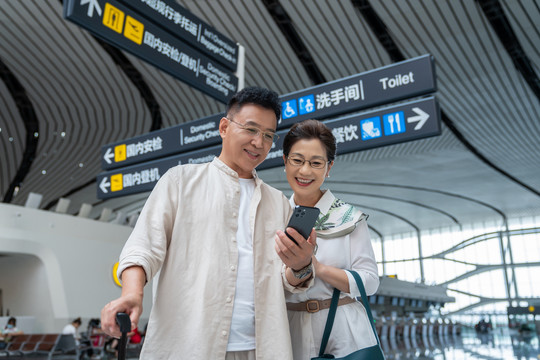 快乐的老年夫妇在机场使用手机