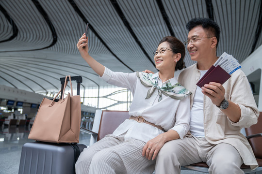 快乐的老年夫妇在机场用手机自拍