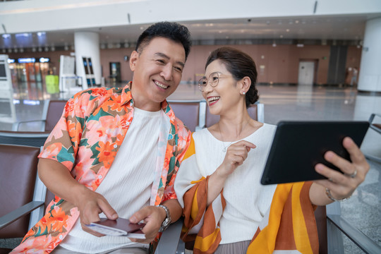 快乐的老年夫妇在机场使用平板电脑