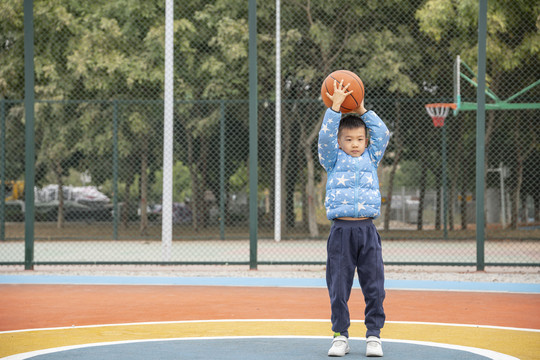 学校操场上打篮球的小男孩